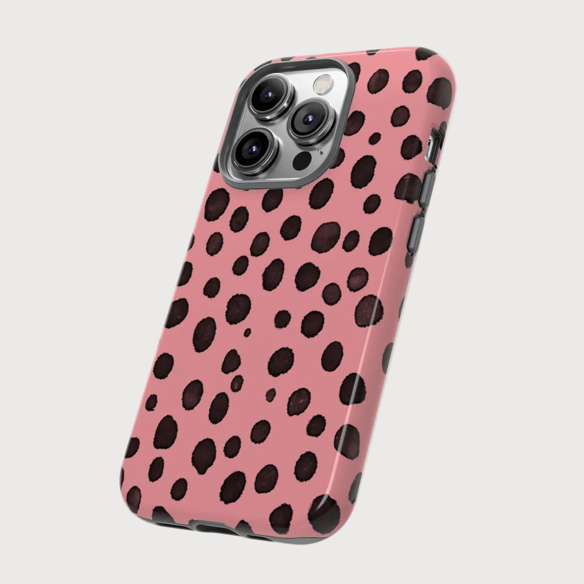 Phone case with pink background and black polka dots on a light gray background