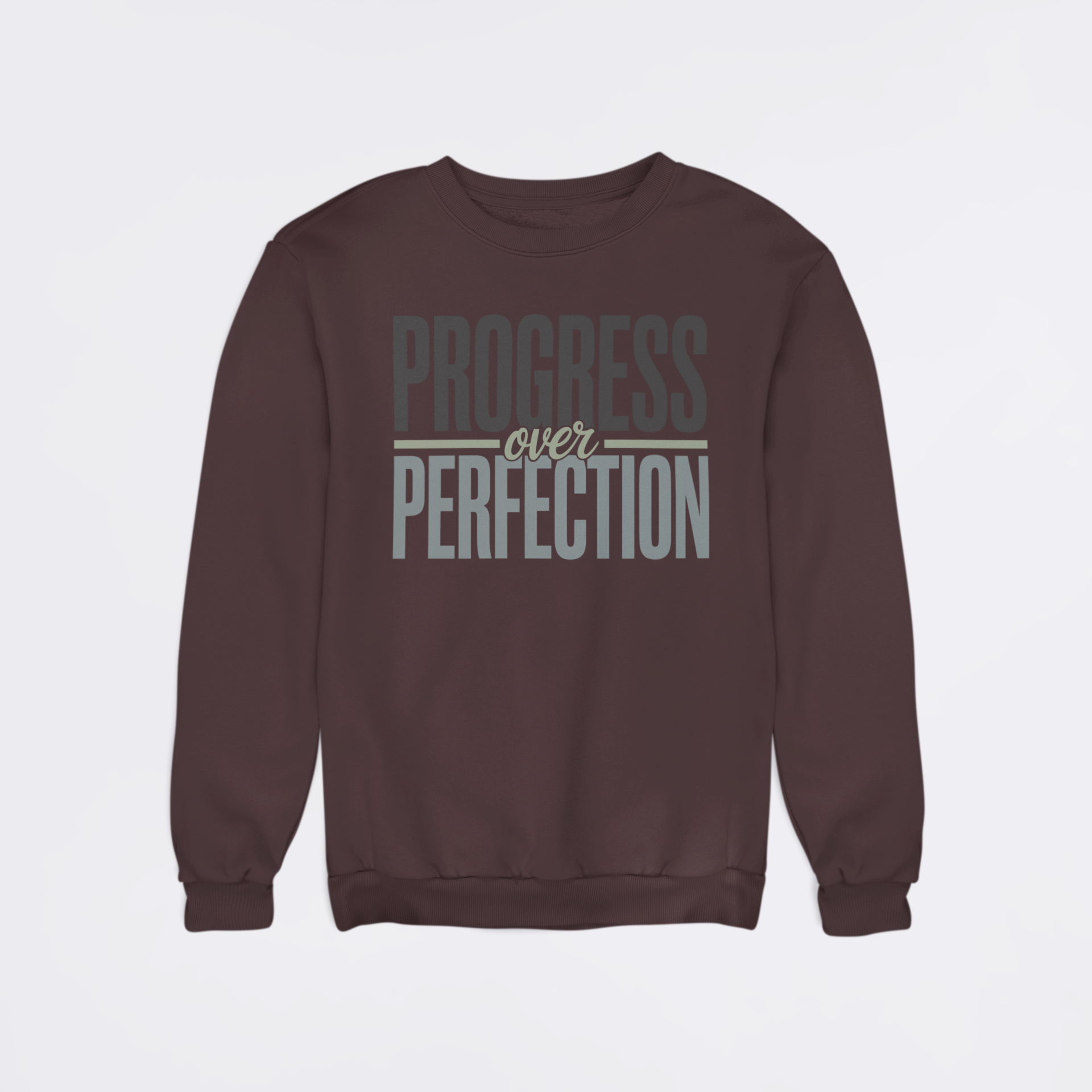 Brown sweatshirt with 'Progress over Perfection' text on a light gray background