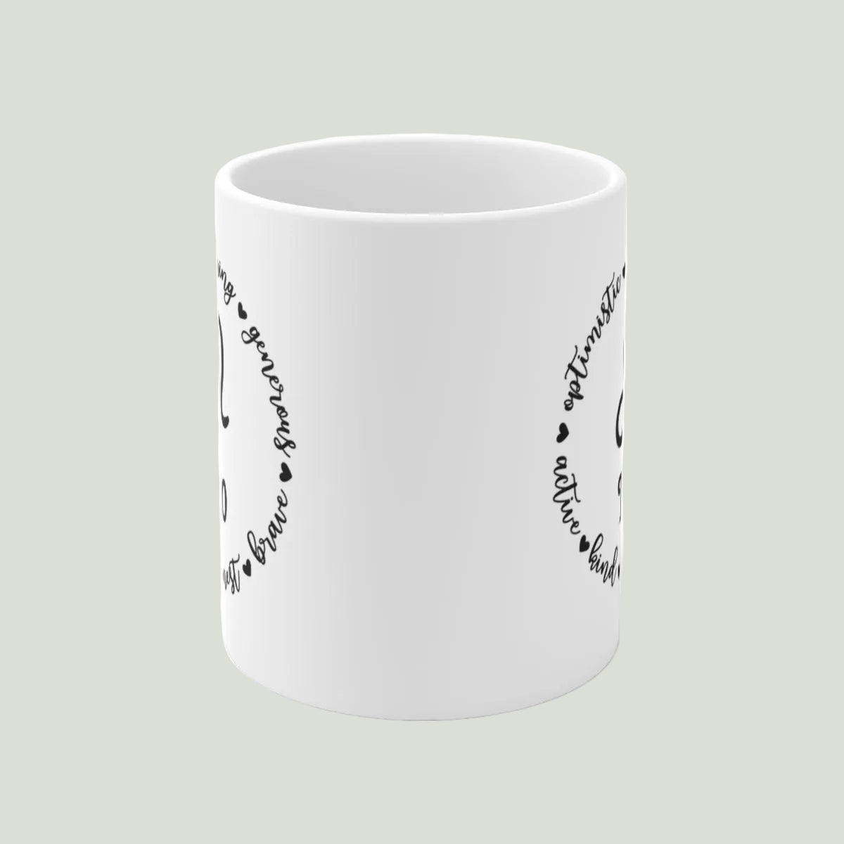White mug with black text and heart designs on a light gray background